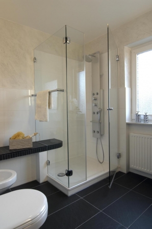 Dusche mit Duschpanell und angeformter Sitzbank in schwarz.
