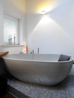 Ovale freistehende Wanne aus Mitek schmiegt sich an die Badwand.