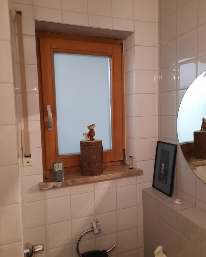 Vorher- Fensterbereich mit Holzrahmen und dekorativer Ablage im Gäste-WC